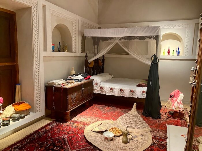 Traditional bedroom at Bait Al Naboodah with four poster bed, chest and floor food mat