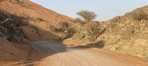Dirt track between mountain and desert in Al Ghayl area
