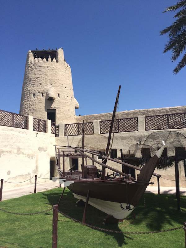 Umm al Quwain Fort  and Museum tower and inner courtyard with a wooden boat
