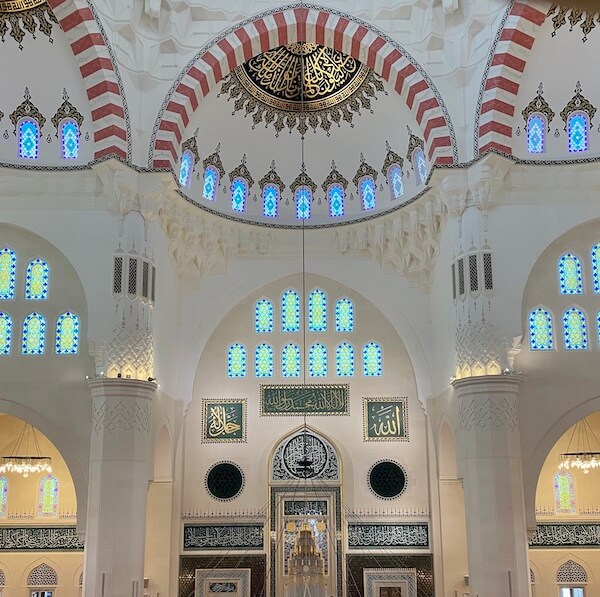 interior of sharjah grand mosque in white, gold and red