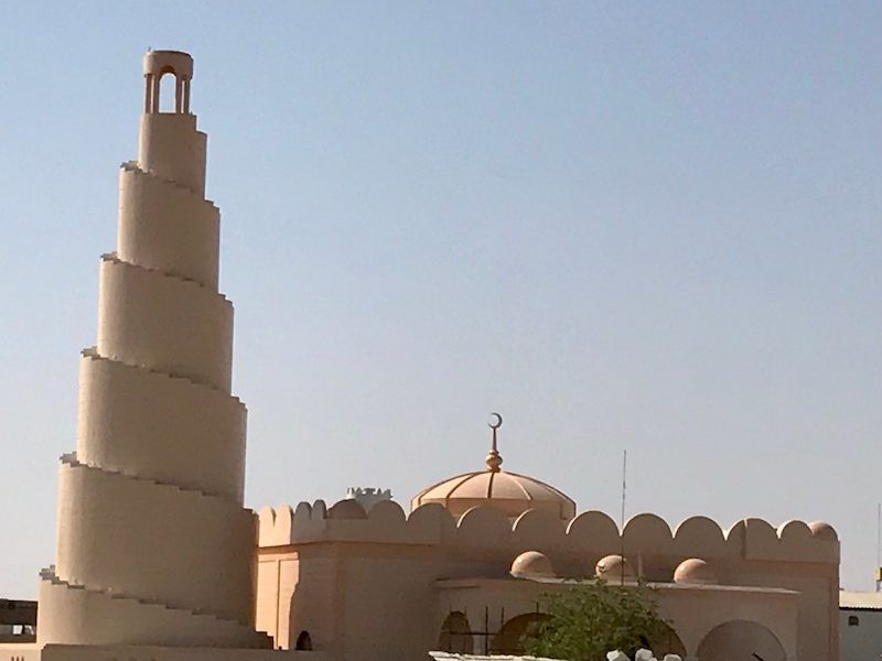 thick spiral minaret and low mosque with low dome, all in sandy shade