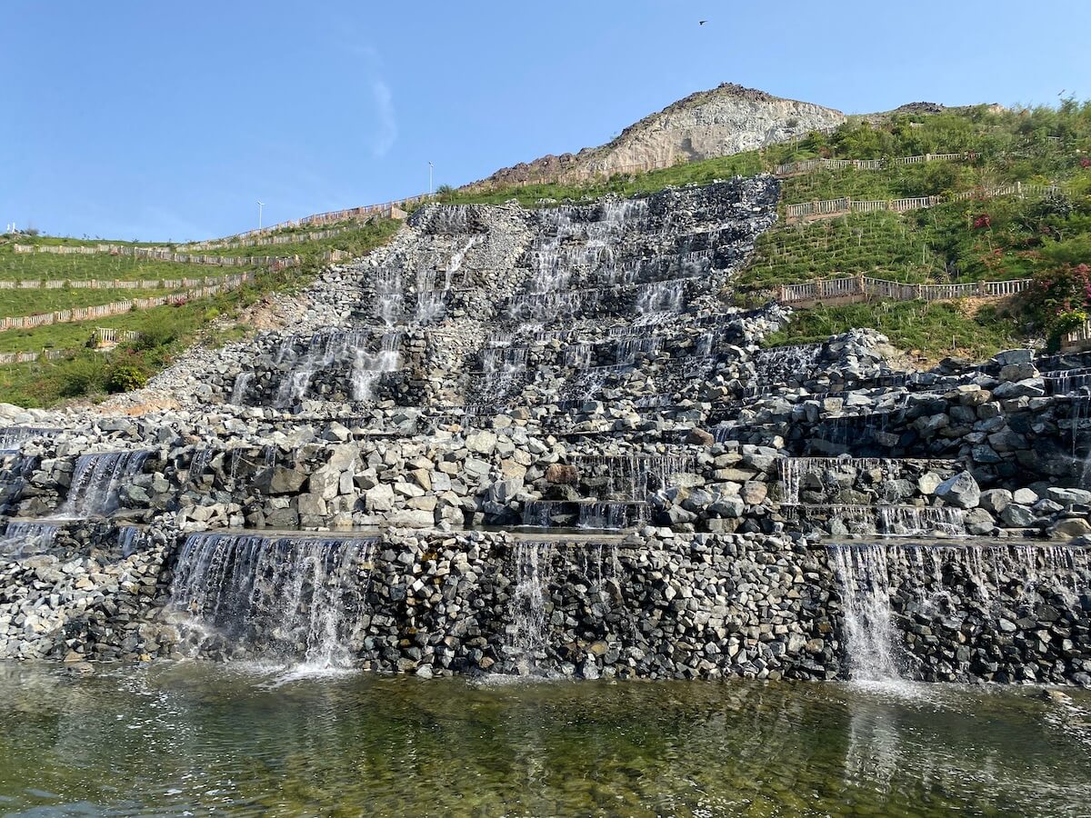 artificial waterfall cascading down rocky steps into a lake
