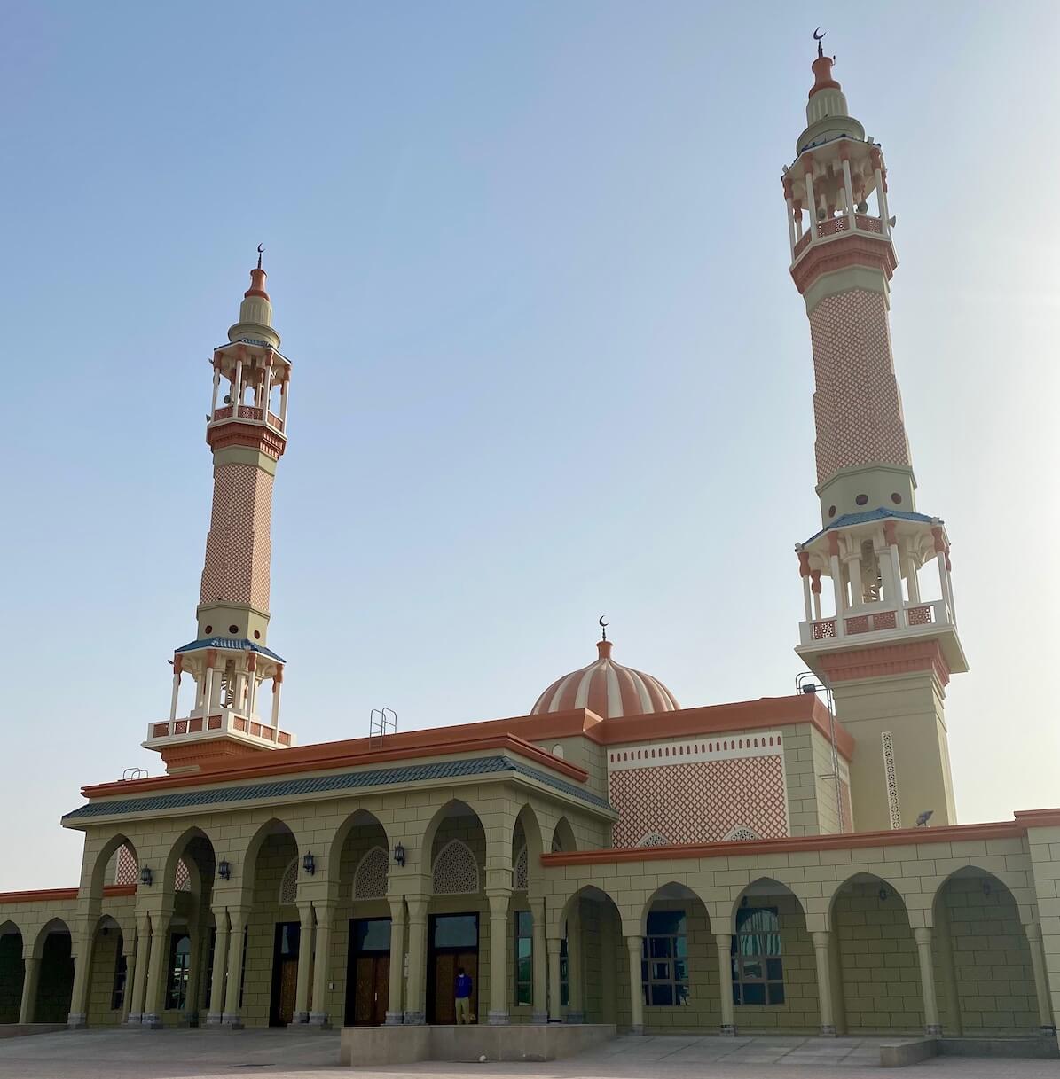 Mosque with red and white stripe dome and minarets with red patterns
