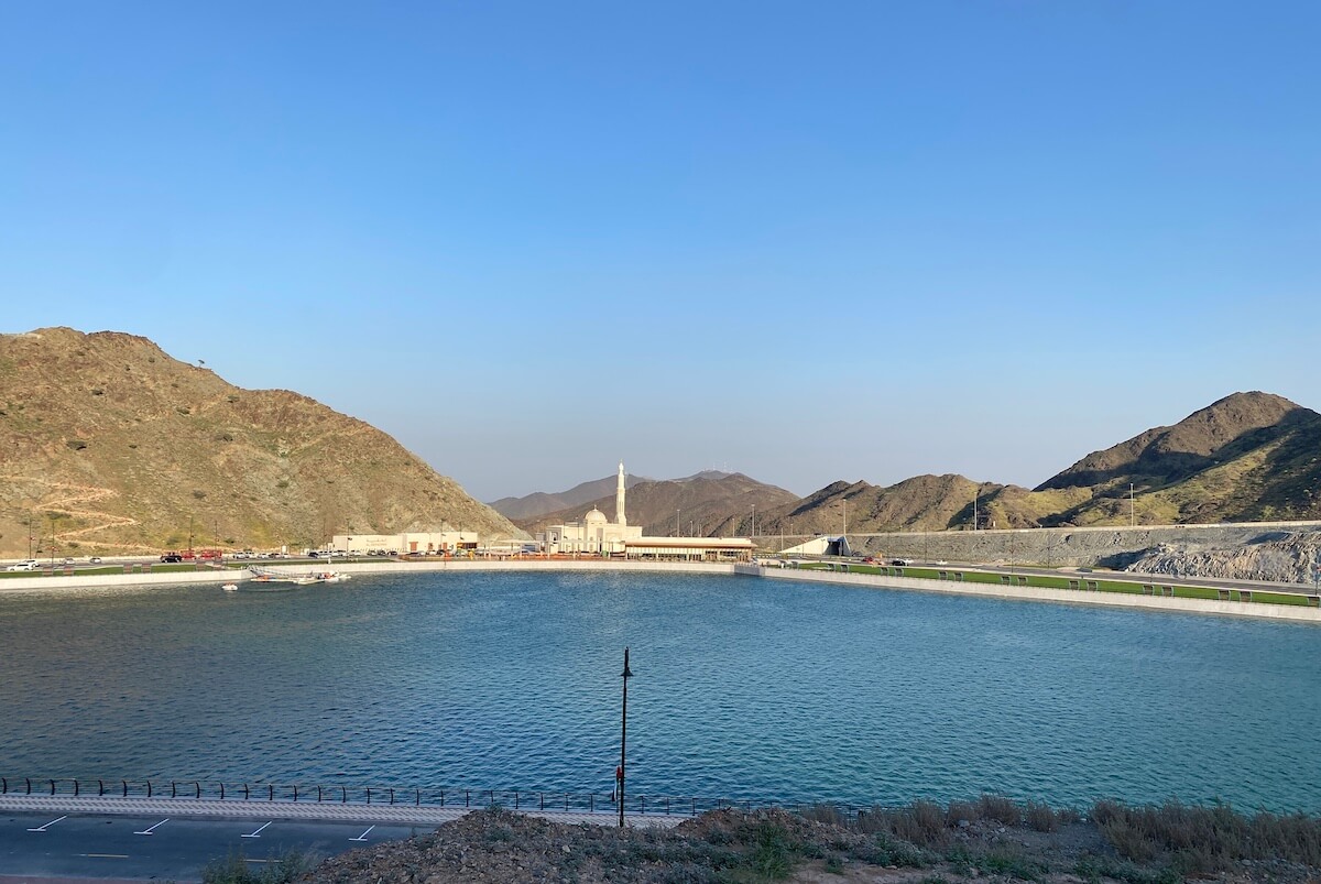 view of reservoir with mosque and mountains in background